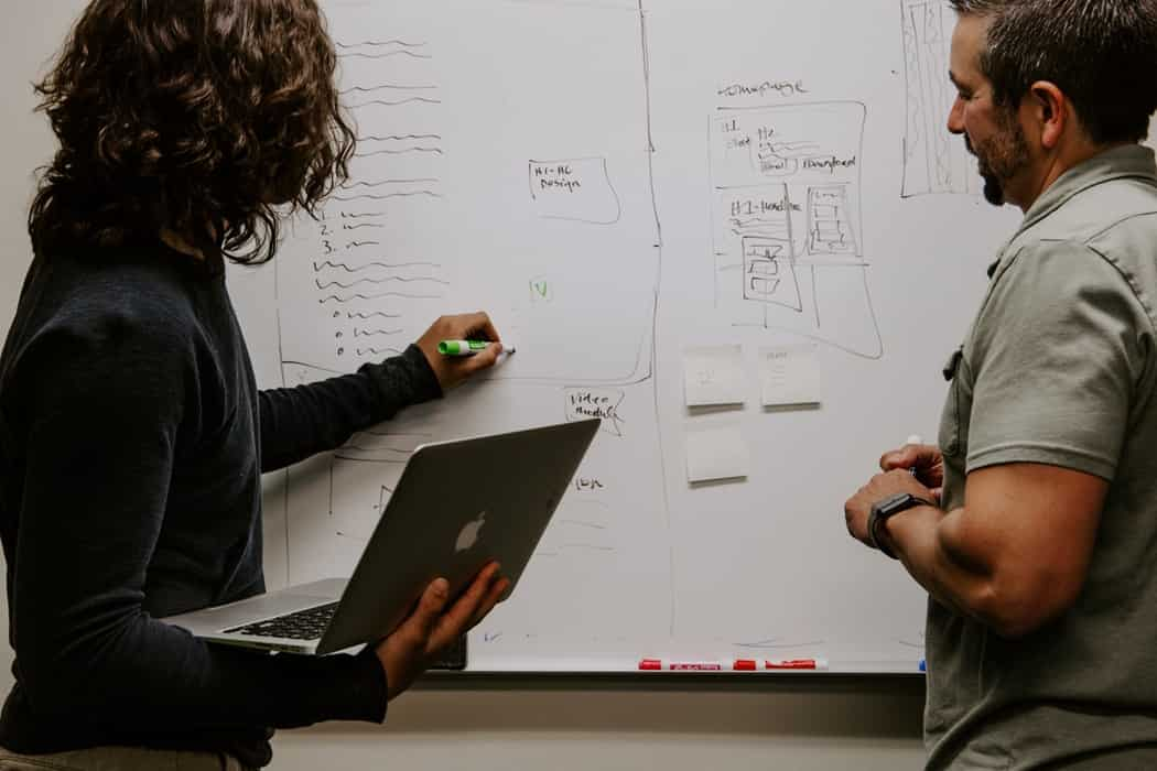 Woman writing on the board to discuss with man